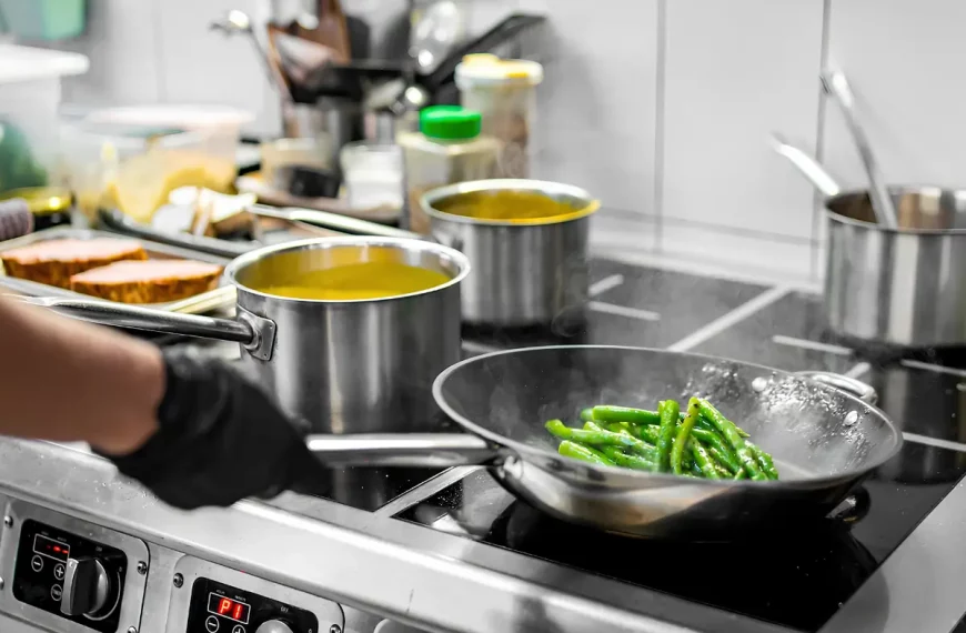 Uma pessoa cozinhando em um fogão industrial com panelas de alumínio.
