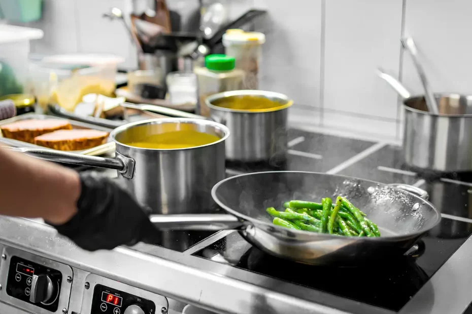 Uma pessoa cozinhando em um fogão industrial com panelas de alumínio.
