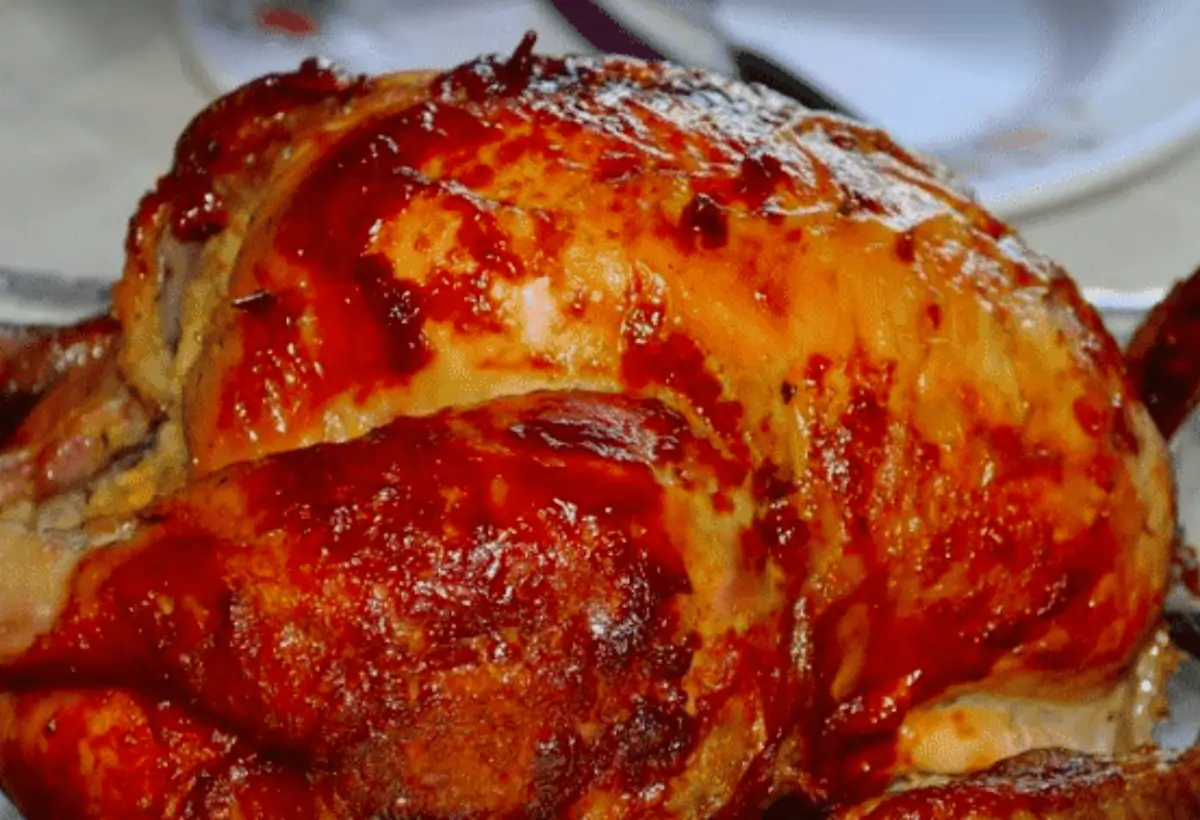 Um frango assado na panela de pressão em uma mesa pronto para ser servido.