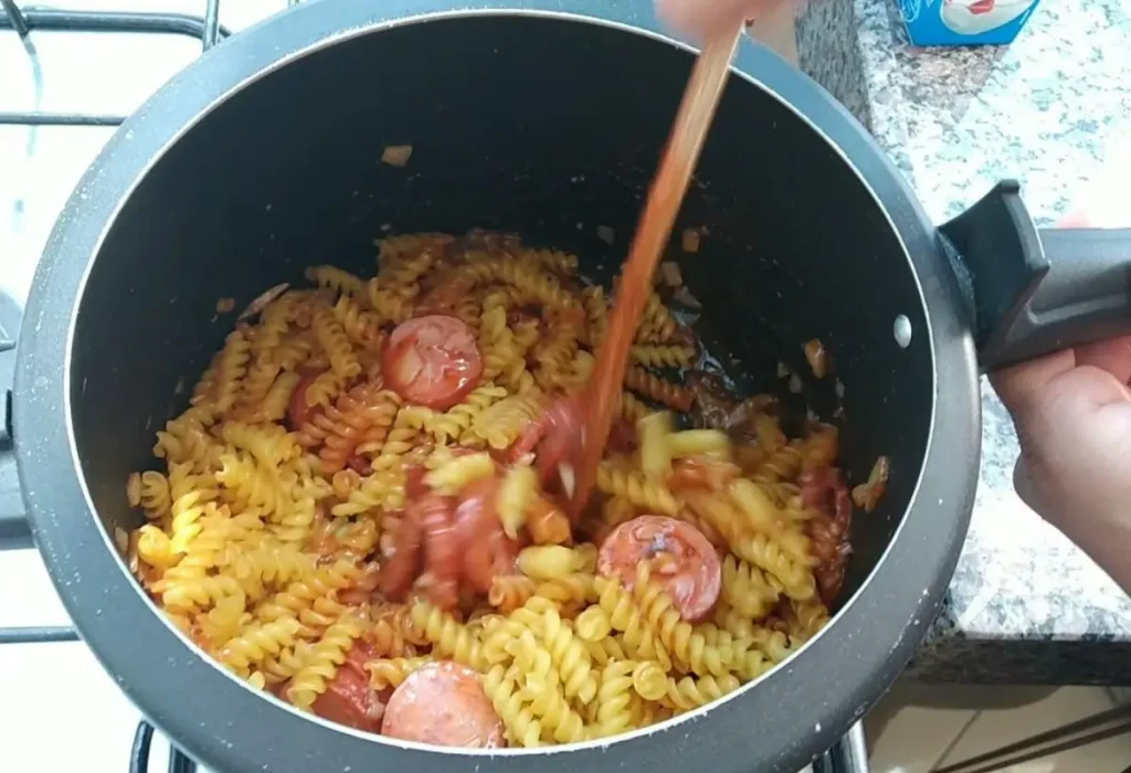 Macarrão com linguiça sendo feito na panela de pressão.