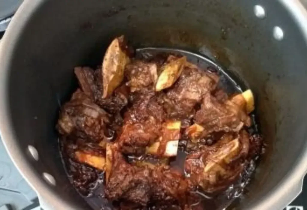 Uma panela de pressão com carne de costela de bafo sendo preparado.