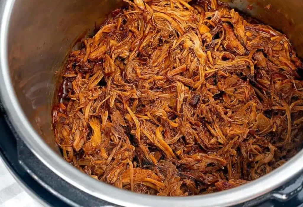 Carne desfiada sendo preparada na panela de pressão.