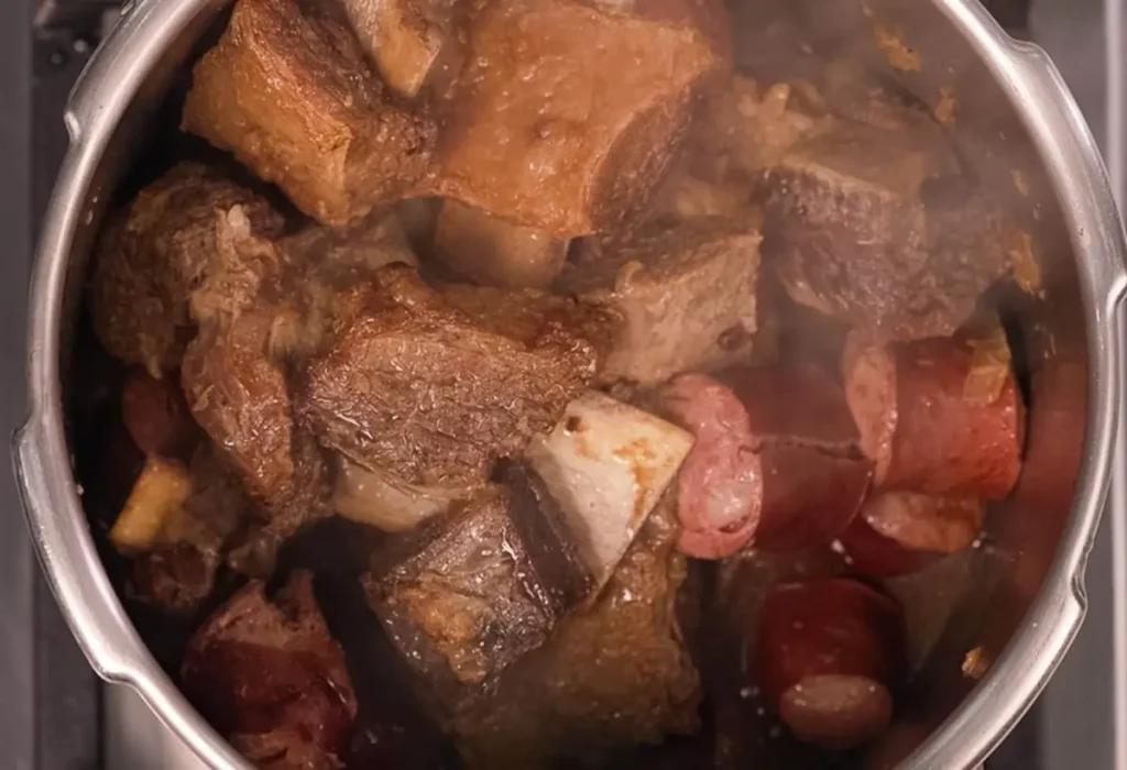 Uma panela com carne de churrasco feito na panela de pressão.