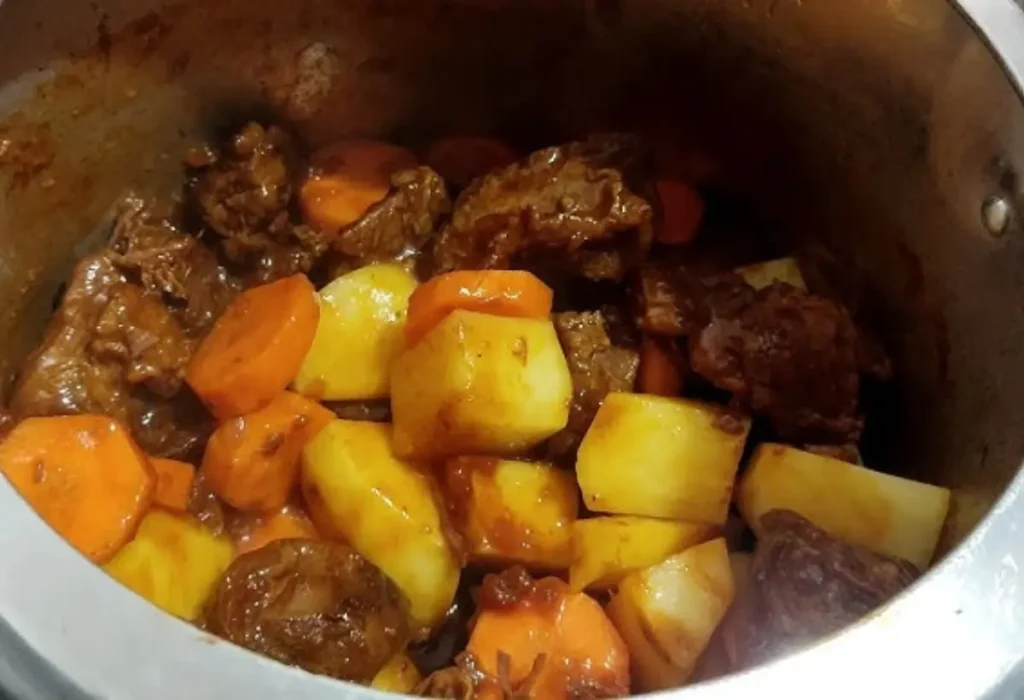 Uma panela de pressão com cozido de carne com legumes.