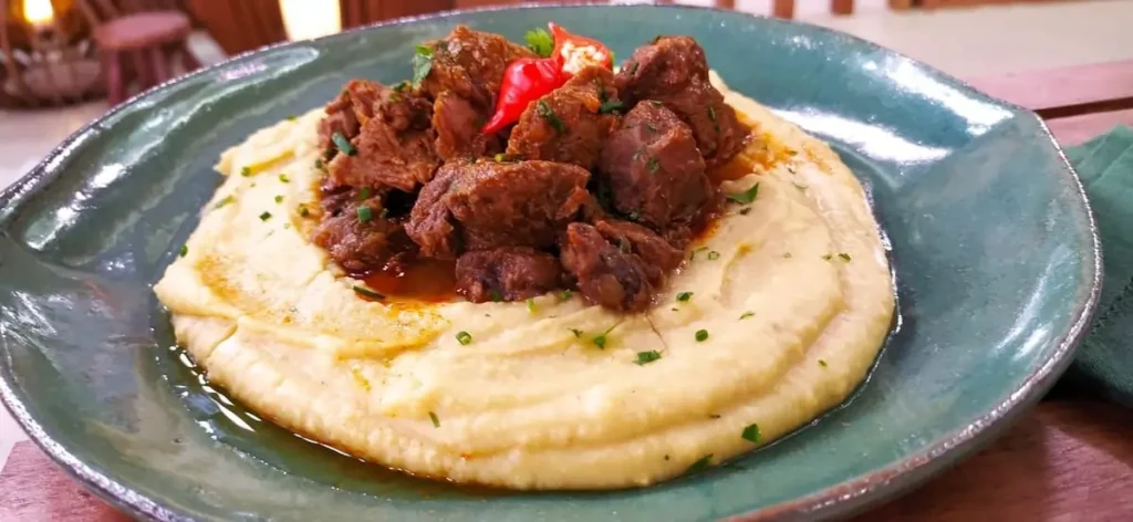 Um prato com músculo com cenoura e purê.