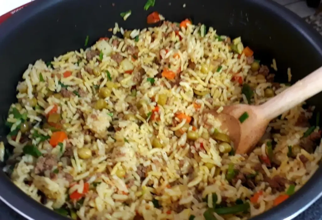 Arroz com carne sendo feito em uma panela de pressão.