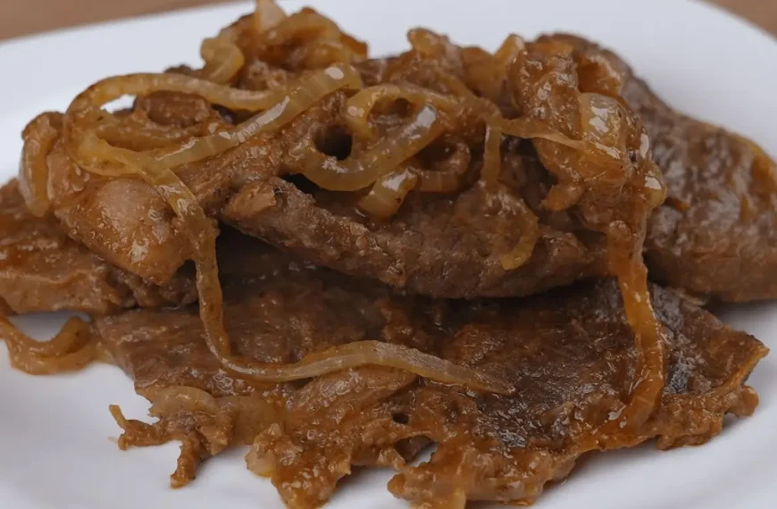Um prato com bife acebolado feito na panela de pressão.