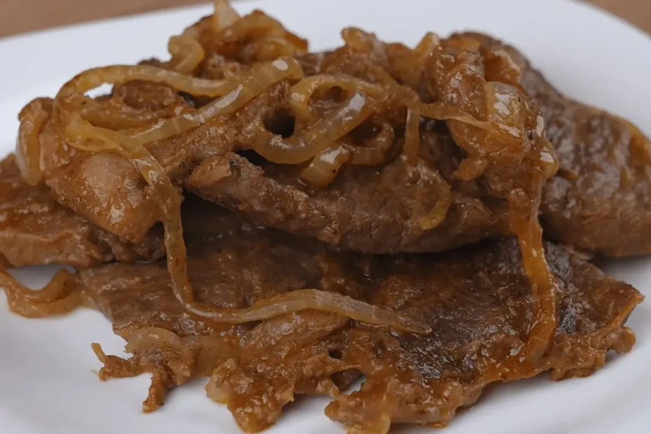 Um prato com bife acebolado feito na panela de pressão.
