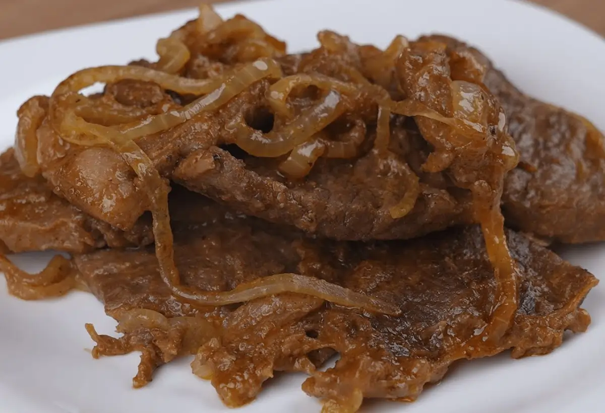 Um prato com bife acebolado feito na panela de pressão.