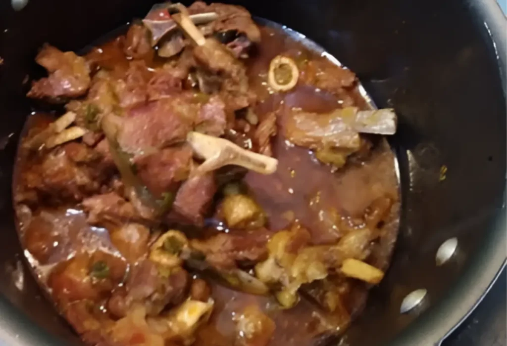 carne de carneiro sendo preparada em uma panela de pressão.