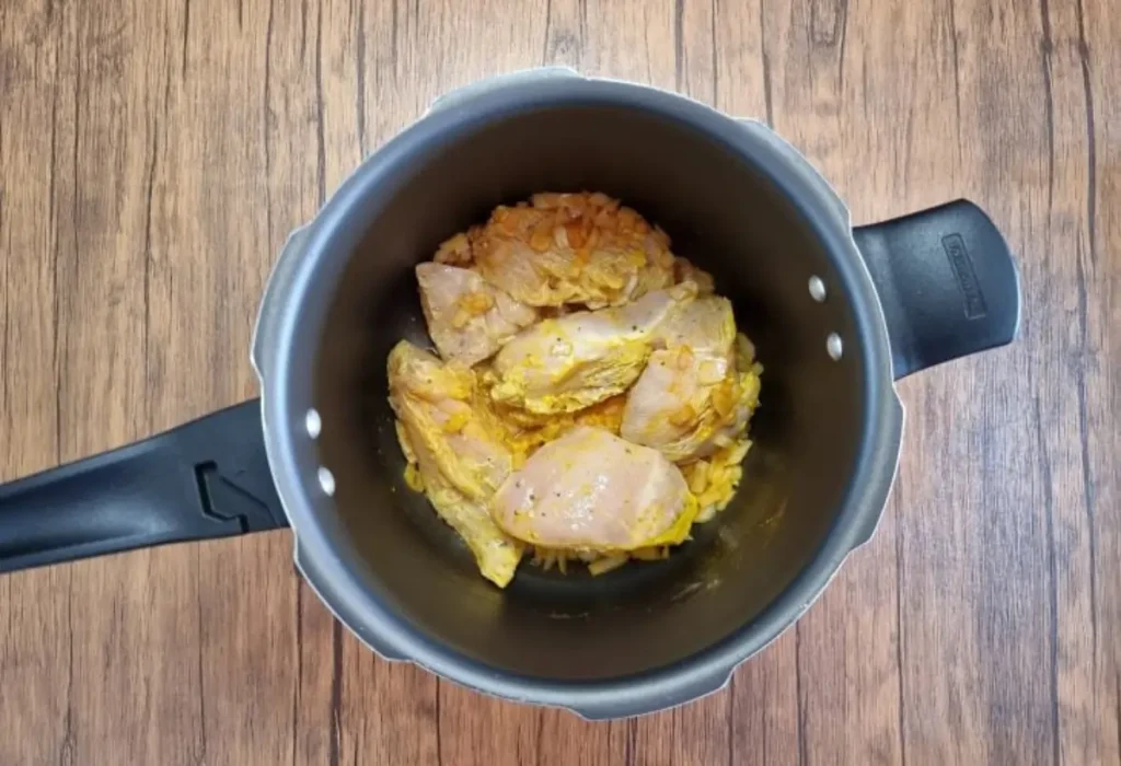 Filé de frango sendo preparado em uma panela de pressão.