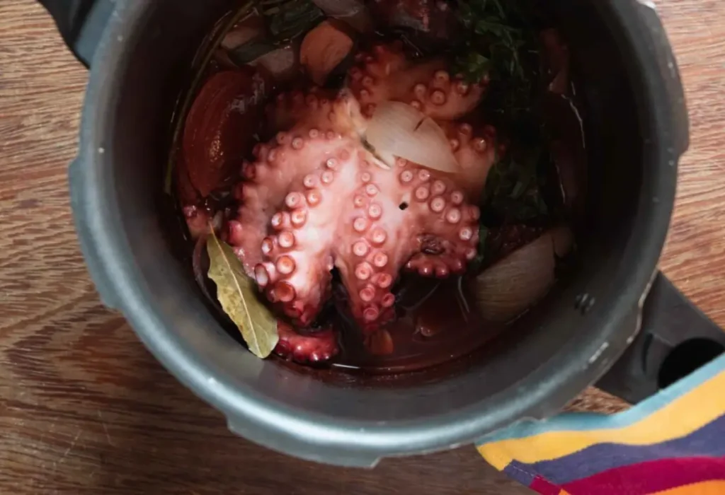 Um polvo sendo preparado em uma panela de pressão.