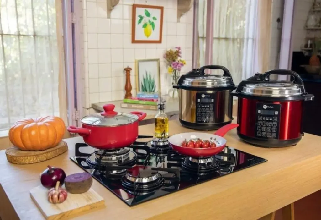Uma bancada com fogão panelas convencionais e duas panelas elétricas de arroz.