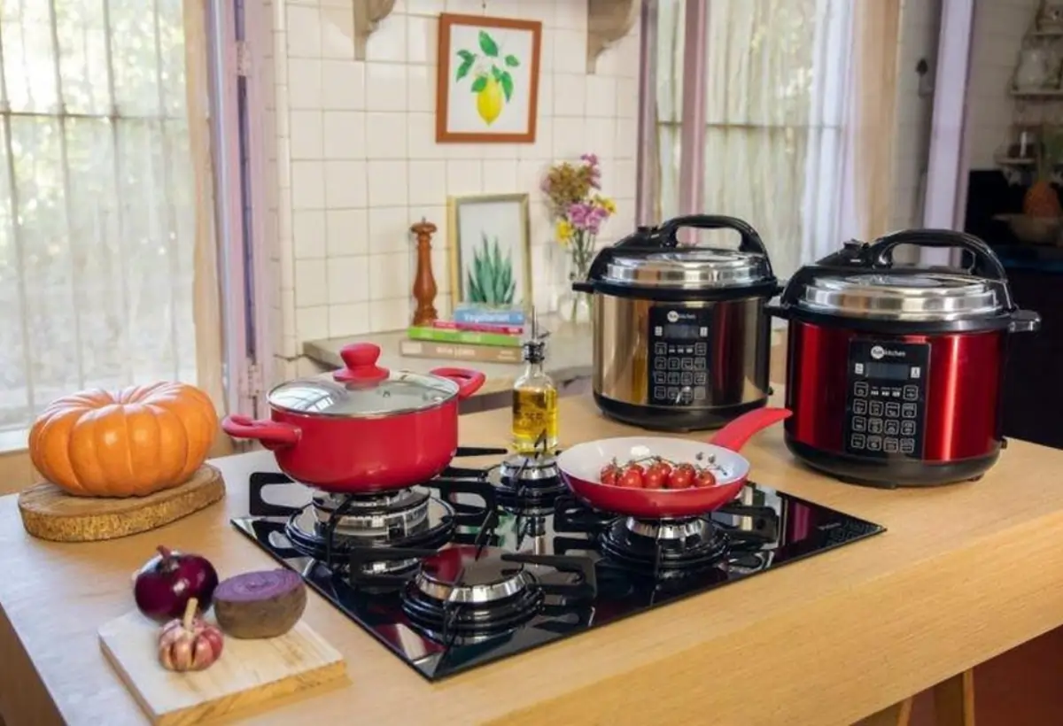 Uma bancada com fogão panelas convencionais e duas panelas elétricas de arroz.
