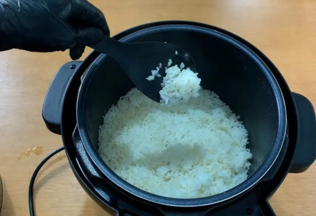 arroz branco sendo preparado em uma panela elétrica de arroz.