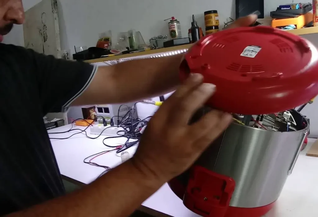 Um homem fazendo o conserto de uma panela elétrica de arroz.
