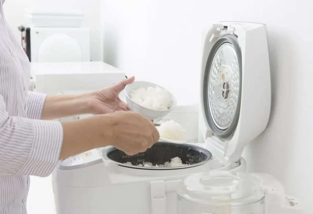 Uma mulher fazendo arroz em uma panelas elétricas.