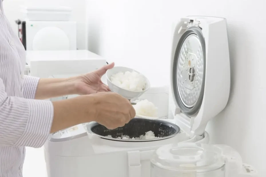 Uma mulher fazendo arroz em uma panela elétrica.