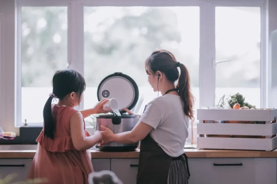Mãe e filha fazendo arroz em uma panela elétrica.