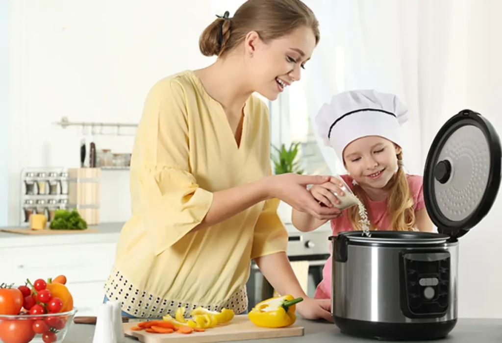 Uma mulher com uma criança fazendo arroz em uma panela elétrica.