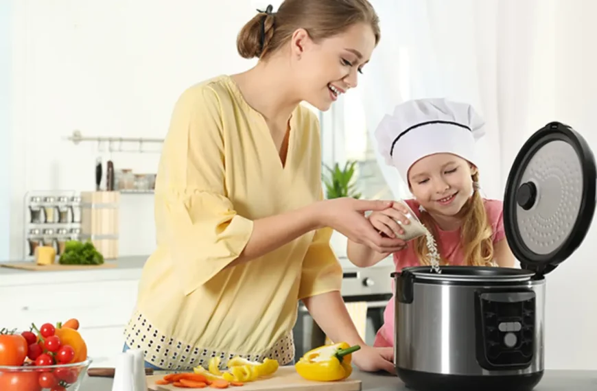 Uma mulher com uma criança fazendo arroz em uma panela elétrica.