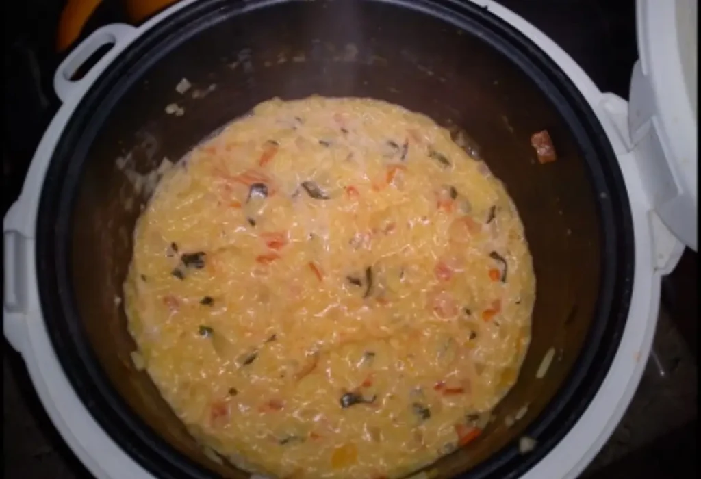Um risoto sendo preparado em uma panela elétrica de arroz.