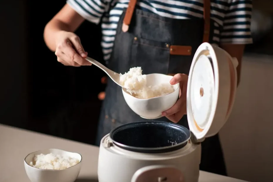 Uma pessoa fazendo arroz branco em uma panela elétrica.