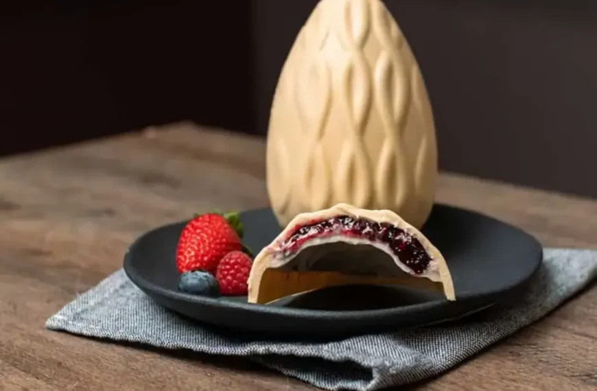 Um ovo de páscoa de chocolate branco com frutas vermelhas.