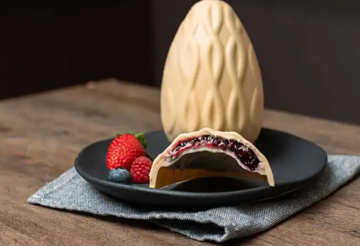 Um ovo de páscoa de chocolate branco com frutas vermelhas.