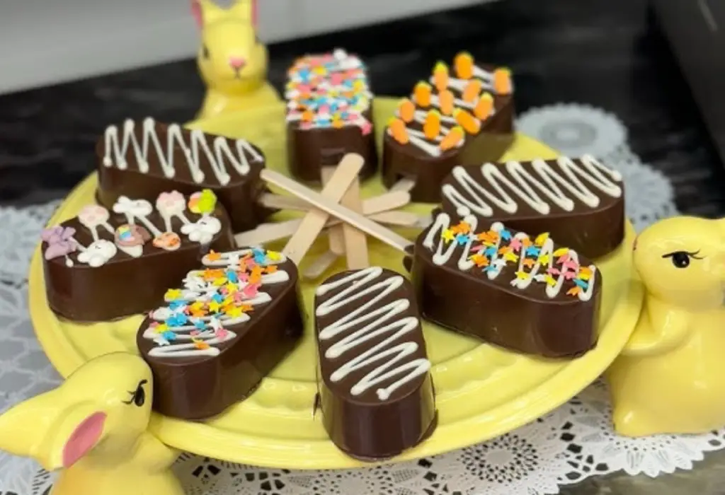 Um prato decorativo de páscoa com vários picolés de chocolate caseiros.